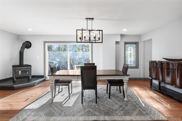 dining room with wood finished floors, a wood stove, recessed lighting, and a healthy amount of sunlight