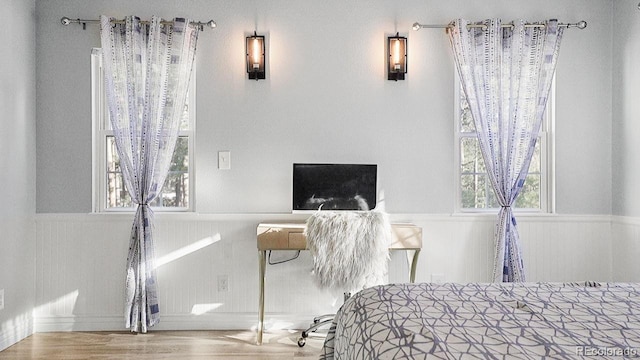 bedroom with a wainscoted wall and wood finished floors