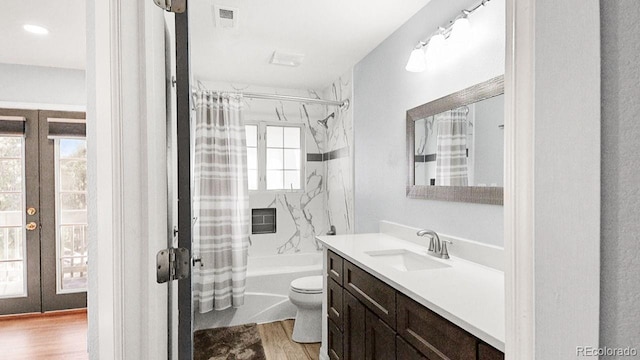 full bath with french doors, toilet, wood finished floors, and vanity