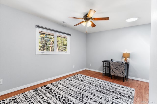 interior space featuring visible vents, baseboards, wood finished floors, and a ceiling fan