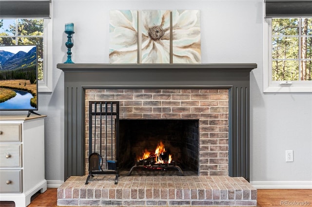 details with baseboards, a brick fireplace, and wood finished floors