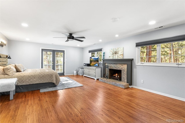 bedroom featuring visible vents, a brick fireplace, recessed lighting, french doors, and wood finished floors