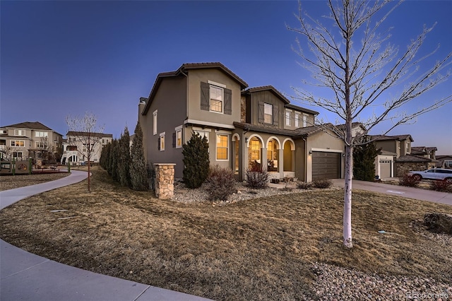 view of front of home featuring an attached garage, a tile roof, driveway, a residential view, and stucco siding