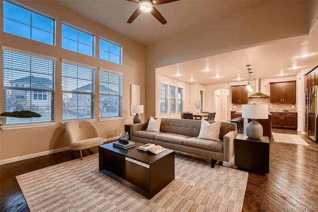 living room with arched walkways, recessed lighting, wood finished floors, a ceiling fan, and baseboards