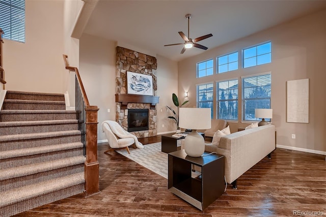 living room with dark wood-style flooring, a fireplace, baseboards, and stairs