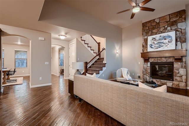 living room with baseboards, arched walkways, stairway, wood finished floors, and a fireplace