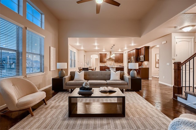 living area featuring baseboards, wood-type flooring, stairway, and a wealth of natural light