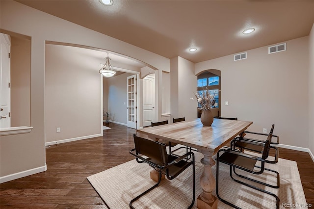 dining space featuring arched walkways, dark wood-style flooring, and visible vents