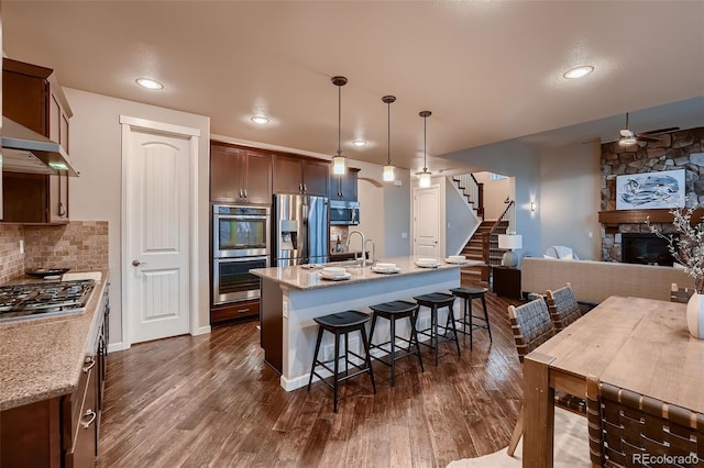 kitchen featuring tasteful backsplash, stainless steel appliances, dark wood-type flooring, and a kitchen breakfast bar