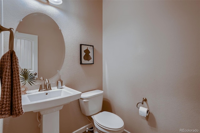 bathroom featuring baseboards and toilet