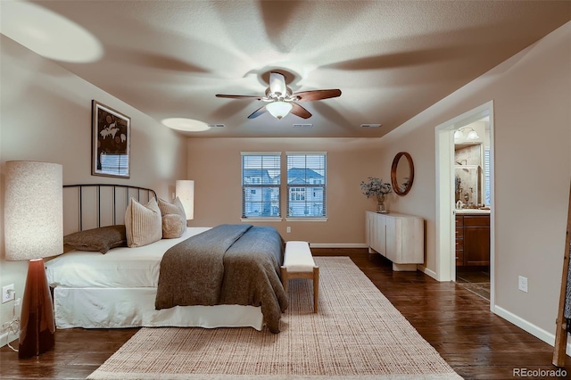 bedroom with dark wood-style floors, ensuite bathroom, visible vents, and baseboards