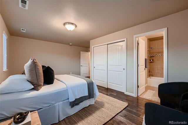 bedroom featuring dark wood-type flooring, a closet, visible vents, and connected bathroom