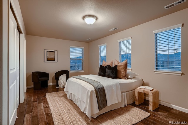 bedroom featuring visible vents, dark wood finished floors, and baseboards