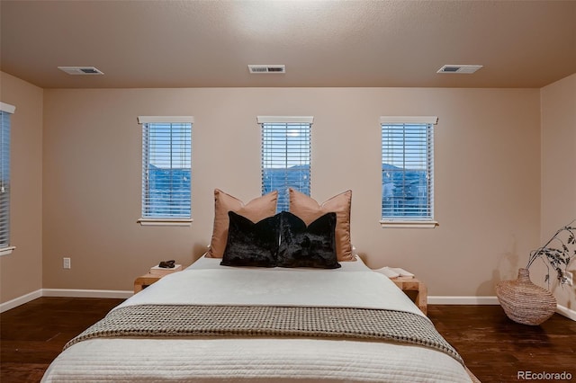 bedroom featuring dark wood-style flooring, visible vents, and baseboards