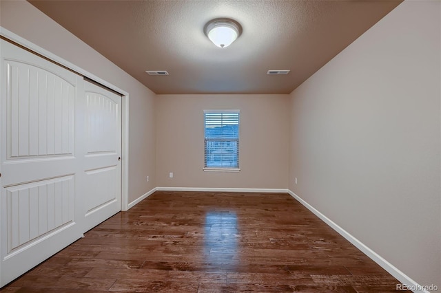 unfurnished bedroom featuring wood finished floors, visible vents, and baseboards