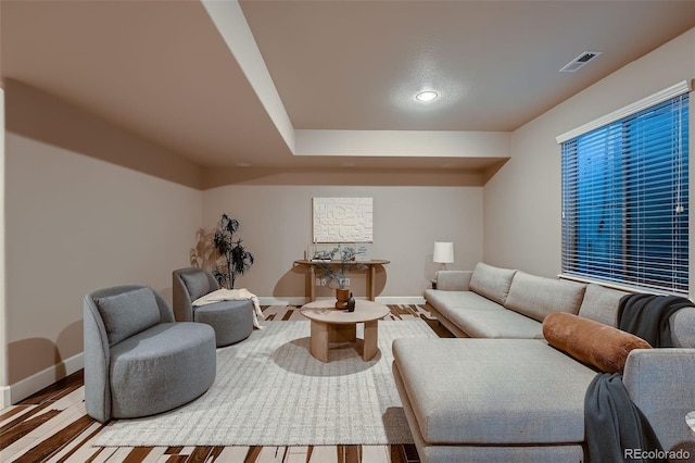 living room with visible vents, baseboards, and wood finished floors