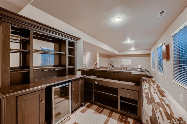 kitchen featuring beverage cooler, open floor plan, light wood-type flooring, and visible vents