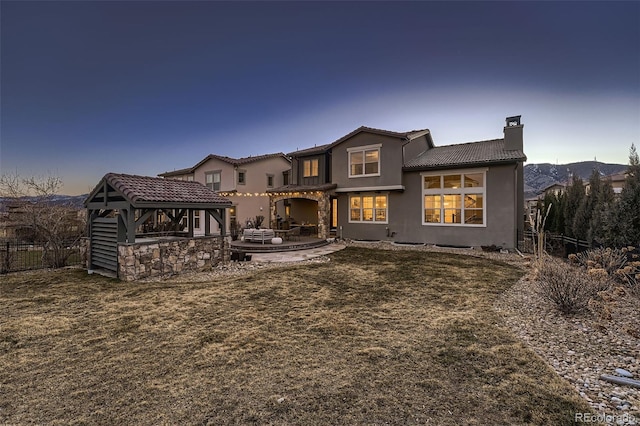 rear view of house with a tiled roof, a chimney, a patio area, and fence