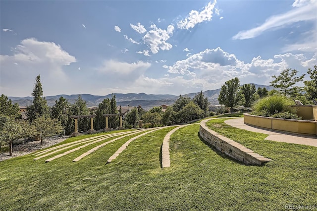 view of property's community with a lawn and a mountain view