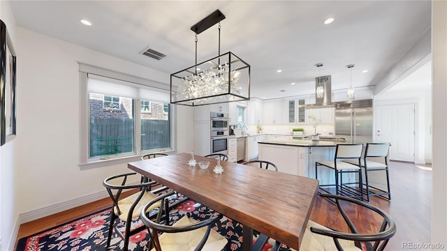 dining room featuring visible vents, baseboards, recessed lighting, and wood finished floors