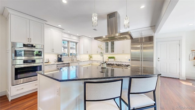 kitchen featuring dark wood-type flooring, white cabinetry, a sink, stainless steel appliances, and island range hood