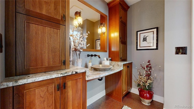 bathroom with double vanity, a sink, tile patterned flooring, and baseboards