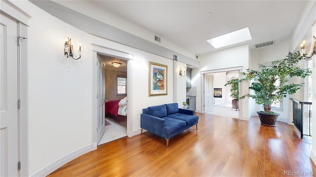 sitting room with light wood finished floors, visible vents, and a skylight