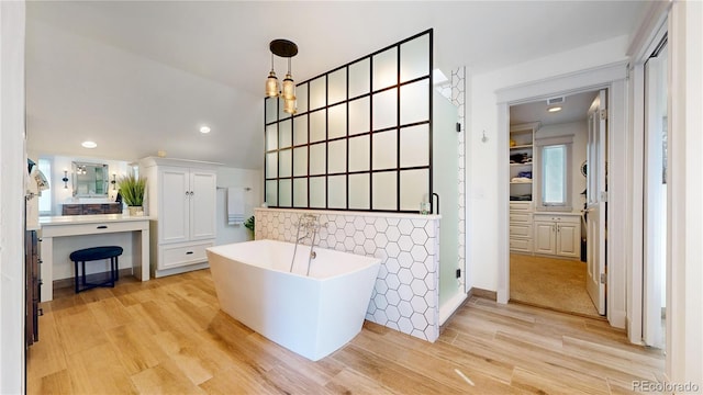full bath featuring a freestanding tub, recessed lighting, backsplash, tiled shower, and wood finished floors