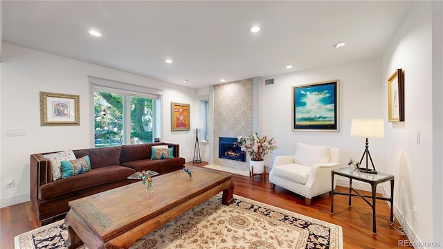living room featuring visible vents, recessed lighting, wood finished floors, a tile fireplace, and baseboards