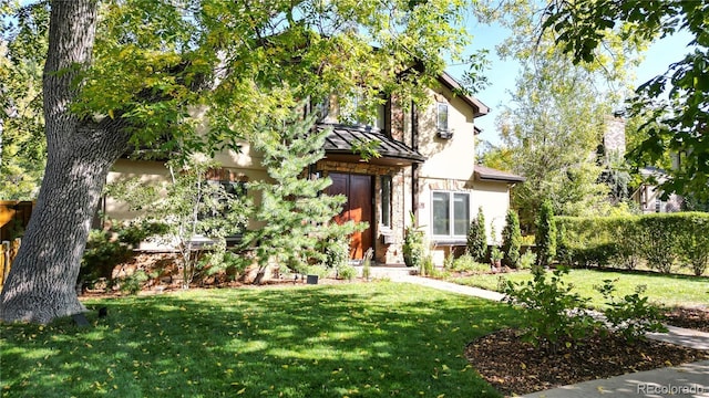 view of front of property featuring a front yard, fence, a standing seam roof, and stucco siding