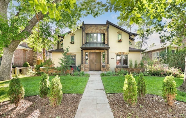 view of front of home featuring a front yard, stucco siding, stone siding, and fence