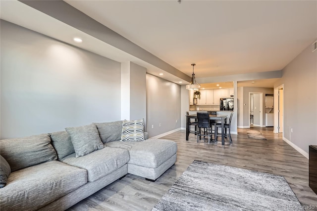 living area with light wood finished floors, recessed lighting, visible vents, and baseboards