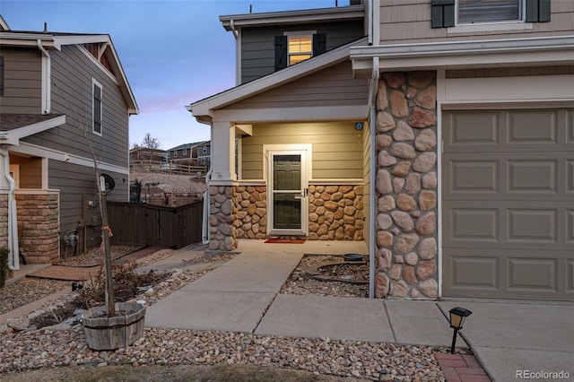 exterior entry at dusk with fence and stone siding