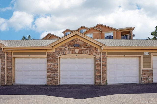 17442 Nature Walk Trl Unit 107, Parker, CO 80134 - view of front of property with community garages, a shingled roof, and stone siding