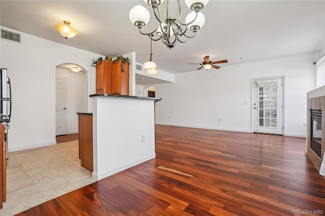 17442 Nature Walk Trl Unit 107, Parker, CO 80134 - kitchen featuring arched walkways, dark countertops, a ceiling fan, a tiled fireplace, and open floor plan