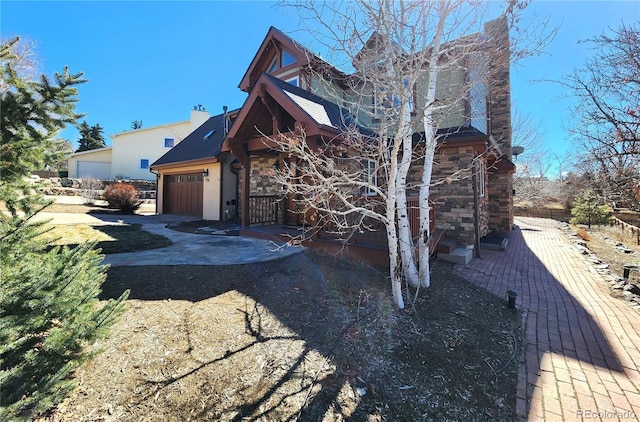 view of front of house featuring stone siding, driveway, and an attached garage