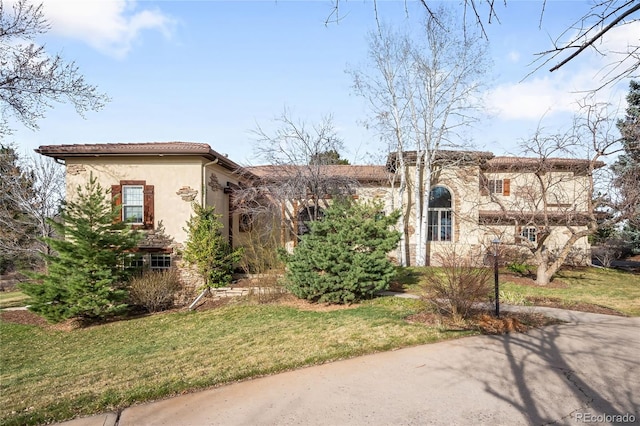 mediterranean / spanish house with stucco siding, stone siding, and a front yard