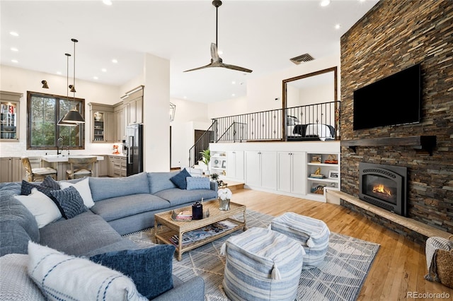 living area with light wood finished floors, visible vents, recessed lighting, and stairway