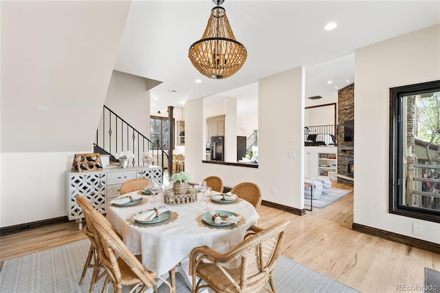 dining space featuring light wood-style flooring, baseboards, an inviting chandelier, recessed lighting, and stairway