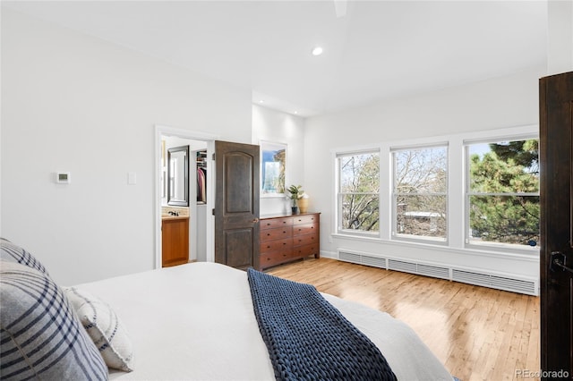 bedroom with a baseboard heating unit, light wood-style flooring, and recessed lighting