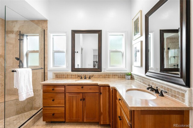 bathroom featuring double vanity, tiled shower, decorative backsplash, and a sink