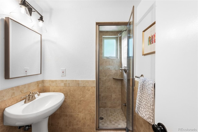 bathroom featuring a shower stall, a sink, and tile walls