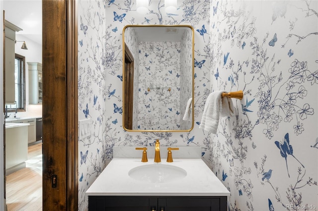 bathroom featuring vanity, wood finished floors, and wallpapered walls