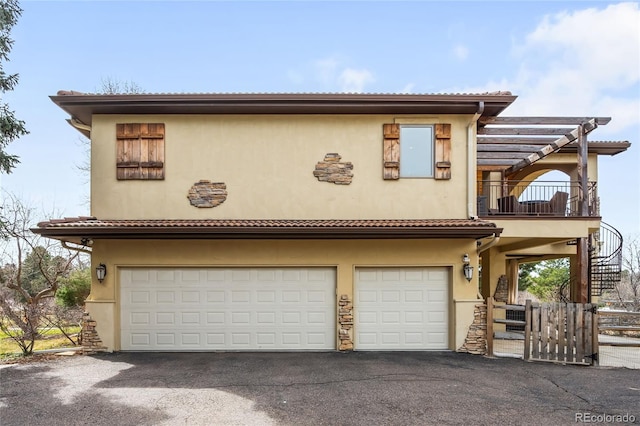 view of front of property featuring driveway, a tiled roof, fence, a garage, and stucco siding