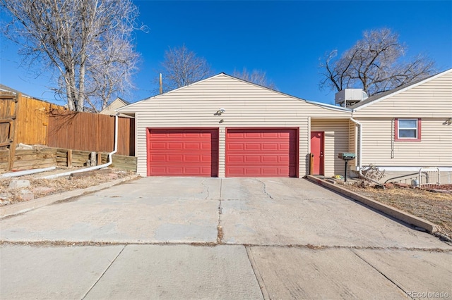 garage with concrete driveway and fence