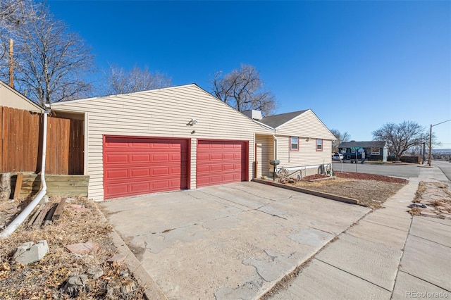 view of front facade featuring driveway, an attached garage, and fence