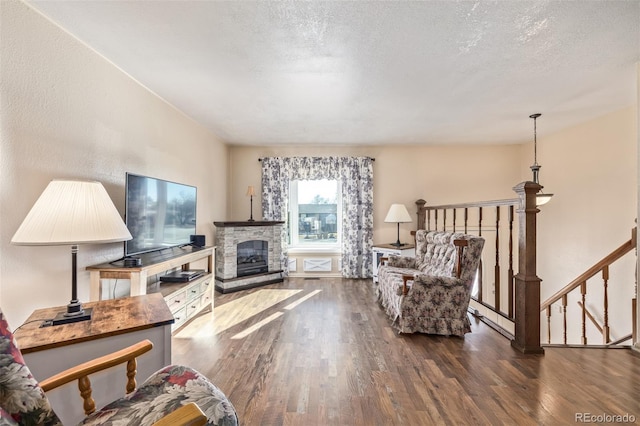 living area featuring a textured ceiling, a fireplace, and wood finished floors