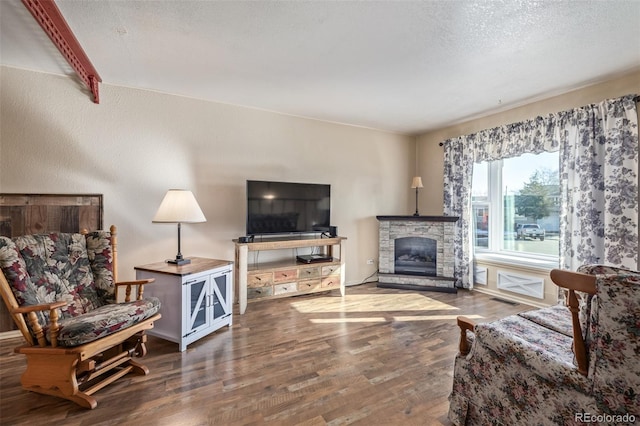 living area with a fireplace, a textured ceiling, and wood finished floors