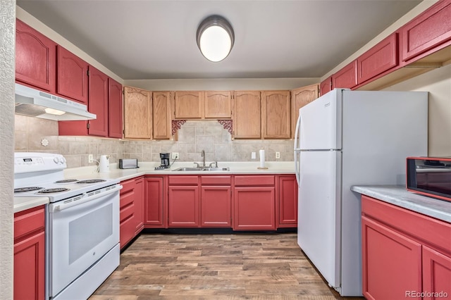 kitchen featuring light countertops, light wood-style floors, a sink, white appliances, and under cabinet range hood