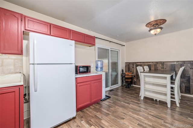 kitchen with dark brown cabinets, light countertops, wood finished floors, and freestanding refrigerator